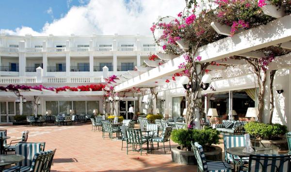 Hotelgeäude mit Bestuhlung und blühenden Bougainvillea