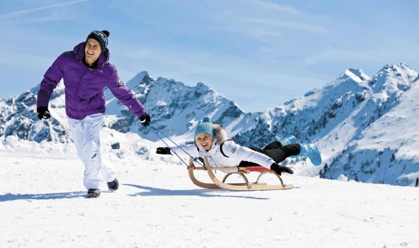 Sich mit Schlitten amüsierende Gäste