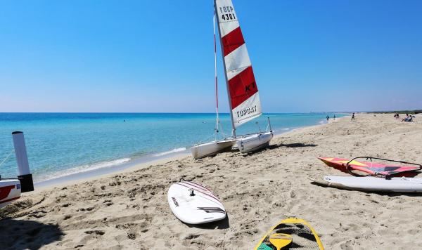 Strand mit Surfboards und kleinen Segelbooten
